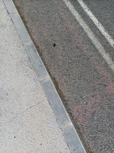 High angle view of an urban street curb showing asphalt and concrete textures.
